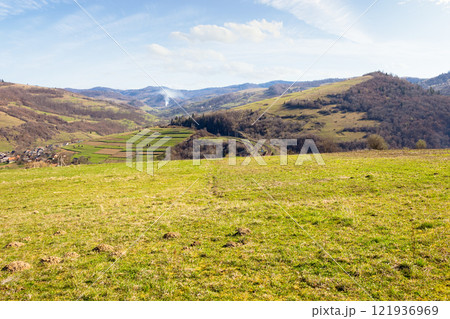 carpathian countryside scenery with fields on the hills and village in the valley. grassy meadow. mountainous rural landscape of ukraine on a sunny day in spring. travel background carpathian countryside scenery with fields on the hills and village in the valley. grassy meadow. mountainous rural landscape of ukraine on a sunny day in spring. travel background 121936969