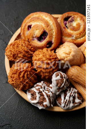 Delicious assortment of baked goods arranged on a wooden platter showcasing various textures and flavors Delicious assortment of baked goods arranged on a wooden platter showcasing various textures and flavors 121937141