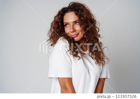 Young woman posing confidently in casual attire against a neutral backdrop Young woman posing confidently in casual attire against a neutral backdrop 121937326