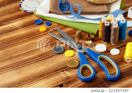 Crafting tools and materials arranged on a wooden table for sewing projects 121937397