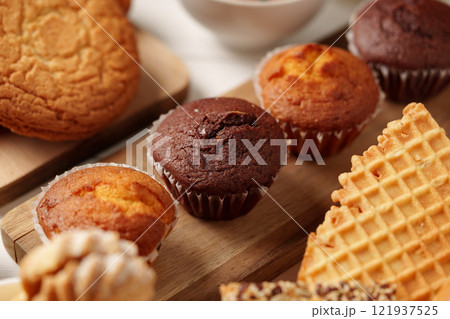 Delicious assortment of baked treats displayed on wooden platters with cookies and muffins 121937525