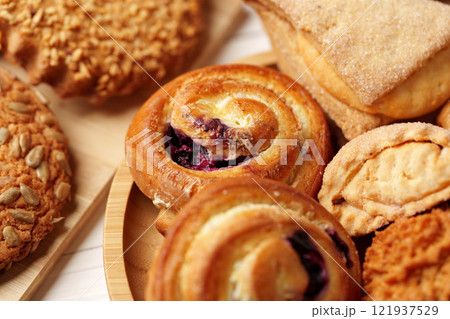 Freshly baked pastries and cookies on a wooden platter in a cozy kitchen setting 121937529