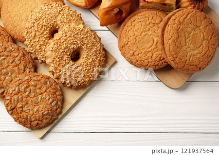 Delicious assortment of freshly baked cookies and pastries on a wooden platter placed on a white wooden table Delicious assortment of freshly baked cookies and pastries on a wooden platter placed on a white wooden table 121937564