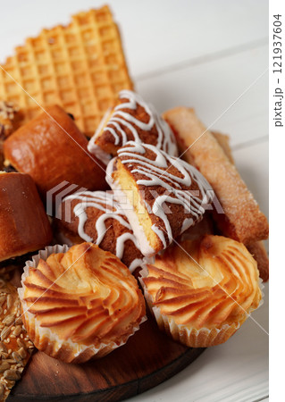 Assorted pastries and sweets arranged on a wooden platter during a food gathering 121937604
