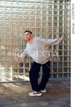 A young man poses against a glass block wall A young man poses against a glass block wall 121937614