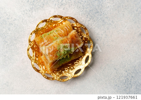Traditional baklava served on a golden plate, showcasing layers of pastry and nuts in a sweet syrup Traditional baklava served on a golden plate, showcasing layers of pastry and nuts in a sweet syrup 121937661