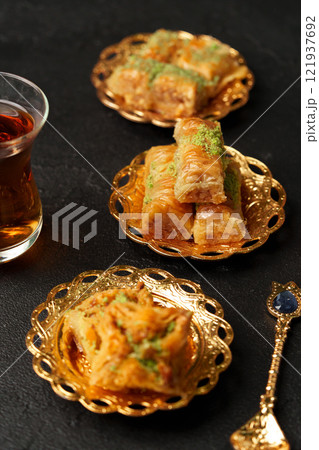 Traditional Middle Eastern desserts served on ornate plates with tea in a cozy setting 121937692