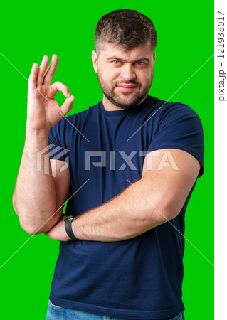 A young man with short hair wearing a navy t-shirt makes an okay gesture against a bright green backdrop A young man with short hair wearing a navy t-shirt makes an okay gesture against a bright green backdrop 121938017