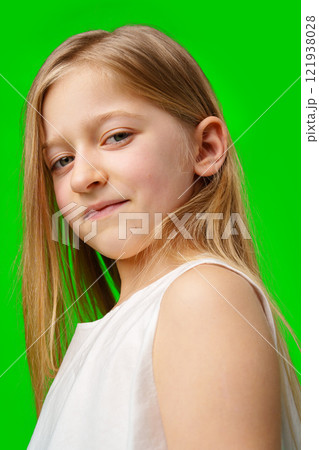 Young girl with long hair poses confidently against a bright green background Young girl with long hair poses confidently against a bright green background 121938028