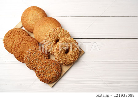 Variety of homemade cookies arranged on a wooden platter against a white background 121938089