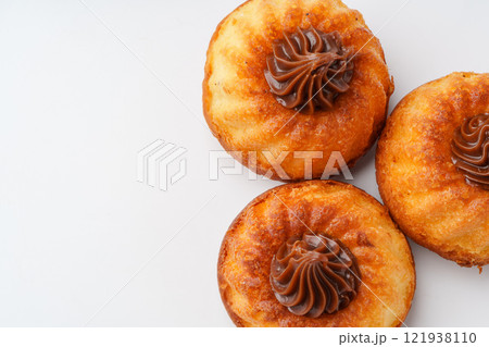 Delicious pastries topped with chocolate cream arranged on a white surface in a tempting display 121938110