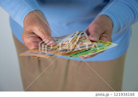 Closeup of a person holding Euro banknotes in their hands 121938188