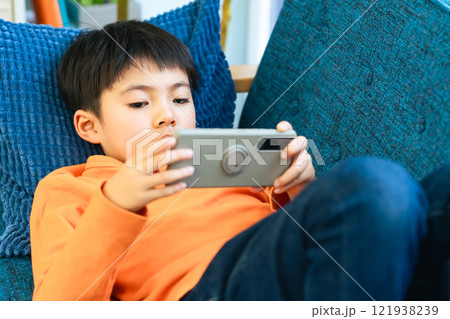 ソファーに寝転んでスマホを使う男子小学生 ソファーに寝転んでスマホを使う男子小学生 121938239