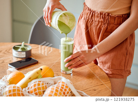 Closeup of a female pouring green healthy smoothie to detox, drinking vitamins and nutrients. Woman nutritionist having a fresh fruit juice to cleanse and provide energy for healthy lifestyle 121938275