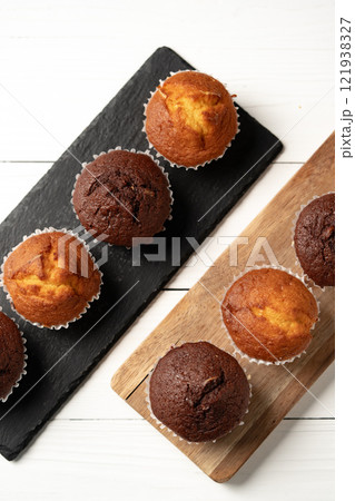 Freshly baked chocolate and vanilla muffins arranged on serving boards ready for enjoyment during a cozy gathering Freshly baked chocolate and vanilla muffins arranged on serving boards ready for enjoyment during a cozy gathering 121938327