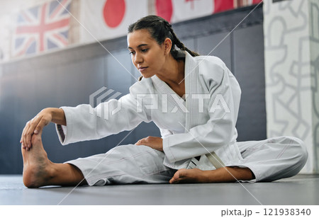 Exercise, fight and workout stretch of a karate school student with focus before training start. Sport woman or coach stretching for an exercise at a dojo studio, performance gym or martial arts club 121938340