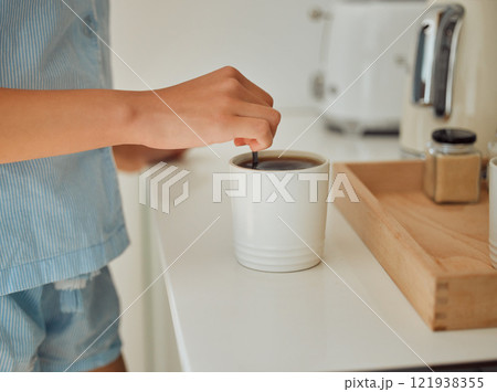 Making fresh, hot morning coffee indoors on a kitchen counter to start the day. Hand closeup of preparing a warm beverage and drink inside with a female standing in pajamas at home Making fresh, hot morning coffee indoors on a kitchen counter to start the day. Hand closeup of preparing a warm beverage and drink inside with a female standing in pajamas at home 121938355