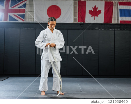 Professional karate student dressing and prepare for practice in a dojo or club. Female mix martial art athlete tying belt in training for a fight, competition or exercise workout in a sport studio Professional karate student dressing and prepare for practice in a dojo or club. Female mix martial art athlete tying belt in training for a fight, competition or exercise workout in a sport studio 121938460