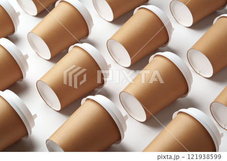 A collection of disposable paper cups arranged in a repeating pattern on a light background A collection of disposable paper cups arranged in a repeating pattern on a light background 121938599