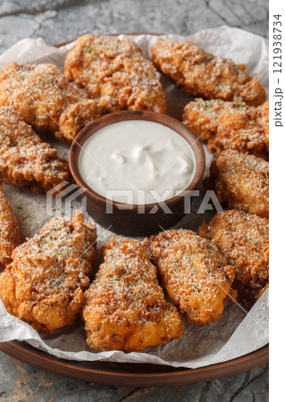 Korean Bburinkle Chicken is a crispy fried chicken with a cheesy, onion, and garlic coating closeup on the plate. Vertical 121938734