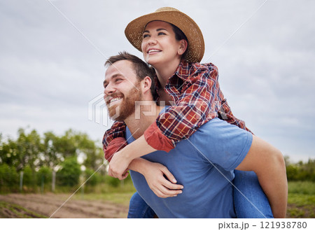 Playful, agriculture farmer couple having fun on a farm, countryside or nature environment enjoying rustic, sustainable living lifestyle. Happy, caring and in love husband giving wife piggyback ride 121938780