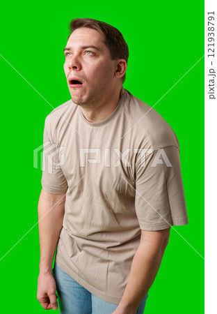 Man making a humorous expression against a bright green background 121938791
