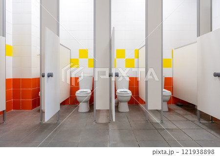 Modern restroom interior featuring clean stalls with vibrant wall tiles and efficient design for user convenience 121938898