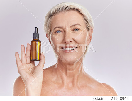Skincare, beauty or makeup product in the hand of a senior woman holding face serum or cosmetic oil in studio on a purple background. Portrait of a female marketing, advertising or endorsing wellness 121938949