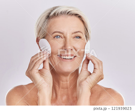 Grooming, skincare and hygiene by a mature woman apply cleanser or toner to her face with cotton pads. Senior female remove makeup and enjoying a routine pamper facial treatment against copy space 121939023
