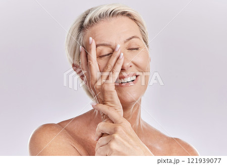 Skincare, wellness and beauty with a senior woman touching her smooth skin and beautiful face with her hand in studio on a grey background. Natural, health and skin care with a female feeling happy 121939077