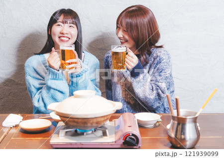 カニ鍋を前に乾杯をする若い女性二人【撮影協力・海鮮居酒屋　魚魯こ】 121939099