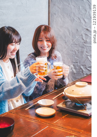 カニ鍋を前に乾杯をする若い女性二人【撮影協力・海鮮居酒屋　魚魯こ】 121939139