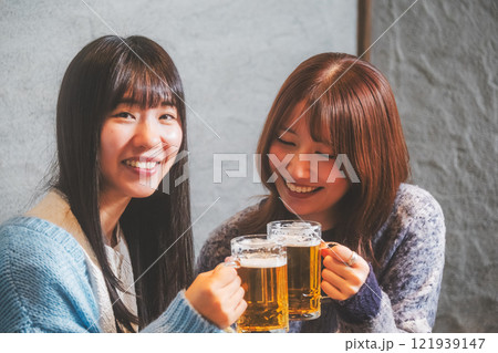 カニ鍋を前に乾杯をする若い女性二人【撮影協力・海鮮居酒屋　魚魯こ】 121939147