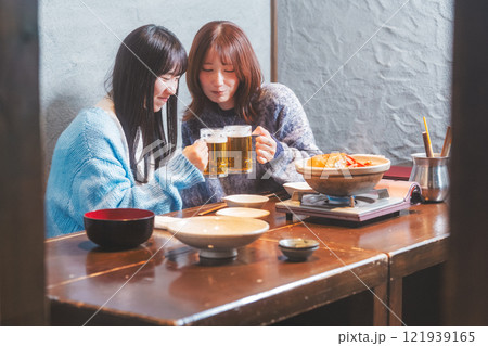 カニ鍋を前に乾杯をする若い女性二人【撮影協力・海鮮居酒屋 魚魯こ】 カニ鍋を前に乾杯をする若い女性二人【撮影協力・海鮮居酒屋 魚魯こ】 121939165