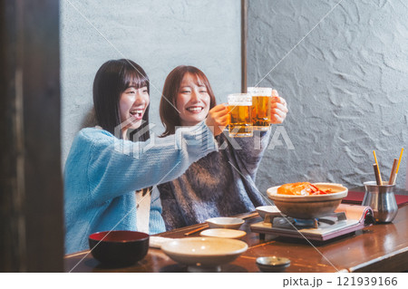 カニ鍋を前に乾杯をする若い女性二人【撮影協力・海鮮居酒屋　魚魯こ】 121939166