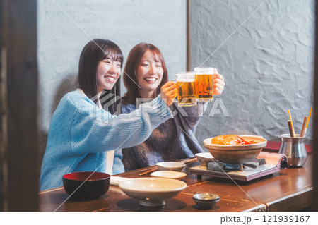 カニ鍋を前に乾杯をする若い女性二人【撮影協力・海鮮居酒屋　魚魯こ】 121939167