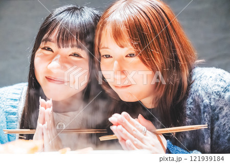 カニ鍋を前にいただきますをする若い女性二人【撮影協力・海鮮居酒屋 魚魯こ】 カニ鍋を前にいただきますをする若い女性二人【撮影協力・海鮮居酒屋 魚魯こ】 121939184