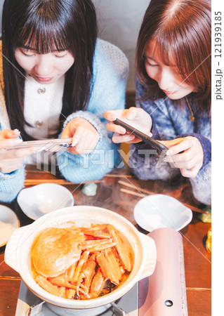 映えるカニ鍋をスマホで撮る若い女性二人【撮影協力・海鮮居酒屋　魚魯こ】 121939185