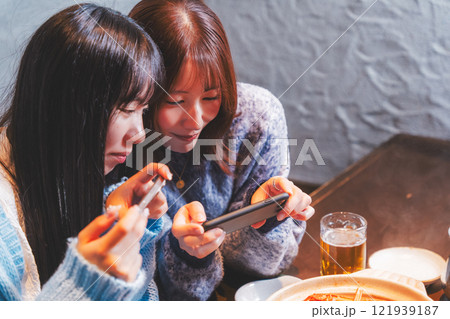 映えるカニ鍋をスマホで撮る若い女性二人【撮影協力・海鮮居酒屋　魚魯こ】 121939187