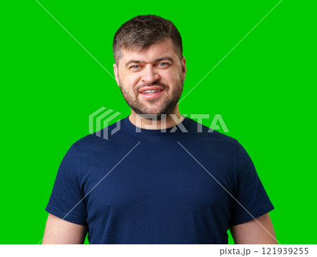 Smiling man wearing a blue shirt poses in front of a bright green background 121939255