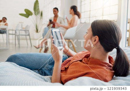 Creative businesswoman, designer or digital marketing agency employee on her phone browsing and searching on a break. Female worker reading or looking for ideas for social media trends on bean bag. Creative businesswoman, designer or digital marketing agency employee on her phone browsing and searching on a break. Female worker reading or looking for ideas for social media trends on bean bag. 121939343