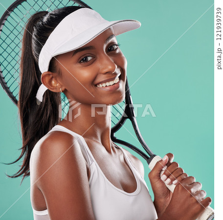 Fit, athlete or female tennis player holding a racket smiling and ready for a competition or match. Portrait of a happy African American sportswoman with equipment against a green studio background Fit, athlete or female tennis player holding a racket smiling and ready for a competition or match. Portrait of a happy African American sportswoman with equipment against a green studio background 121939739