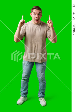 Enthusiastic man pointing upwards against a vibrant green background 121939918