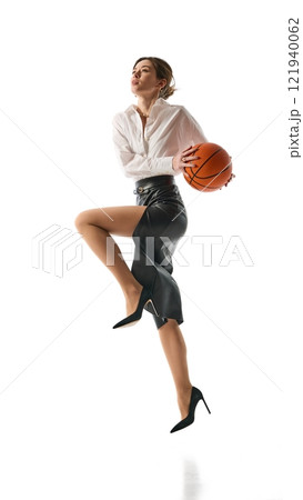 Woman mid-jump with basketball, dressed in formal attire, representing ambition and ability to take bold leaps in career advancement against white studio background. Woman mid-jump with basketball, dressed in formal attire, representing ambition and ability to take bold leaps in career advancement against white studio background. 121940062