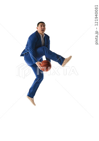 Man in blue suit mid-jump holding basketball with confident expression, capturing ambition and energy against white studio background. 121940081