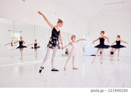 Ballet instructor or teacher teaching a young dancer in a class or dance studio preparing her for a performance. Young little girl learning to be a ballerina getting training for a coach 121940200