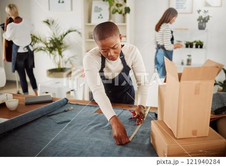 Fashion designer, tailor and creative entrepreneur measuring material and textile for fashionable and trendy clothing in her startup business. Using a tape measure to trim or cut fabric for design 121940284