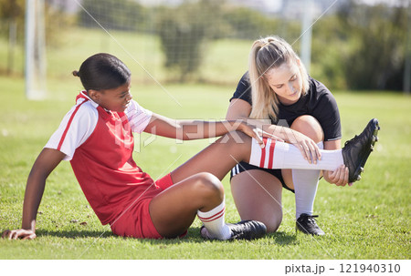 Soccer, sports and injury of a female player suffering with sore leg, foot or ankle on the field. Painful, hurt and discomfort woman getting her pain checked out by athletic trainer on the pitch. 121940310