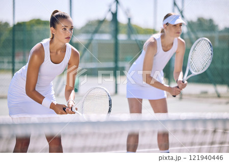 Fit, sporty and female tennis players ready to play a sports match on the court as a team. Active, sportswomen and athletes holding rackets in their hands and concentrating on winning the game. 121940446