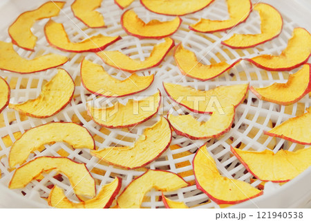 Process of drying apples in a kitchen appliance. Apples in a dryer. Preparing dried fruits at home. Process of drying apples in a kitchen appliance. Apples in a dryer. Preparing dried fruits at home. 121940538